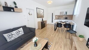 A modern living room with a sofa, coffee table, and a dining area with chairs and a table.