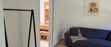 A room with a dark blue sofa, a wooden bench, and a door leading to another room.