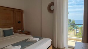 A hotel room with a bed, a nightstand, a round mirror, and a balcony with a view of the sea. - MeThea SeaView Apartments by Greek Pride (Kassandra)