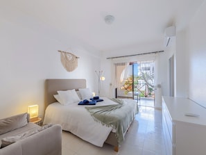 Ein Schlafzimmer mit Bett, Nachttisch und Blick ins Freie.
