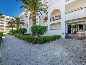 Et moderne hotel med en anlagt sti, palmer og en velholdt have.