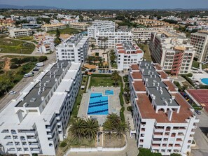 A high-rise residential building with a central courtyard featuring a swimming pool, surrounded by balconies and greenery. - Be My Guest by Interhome (Porches)