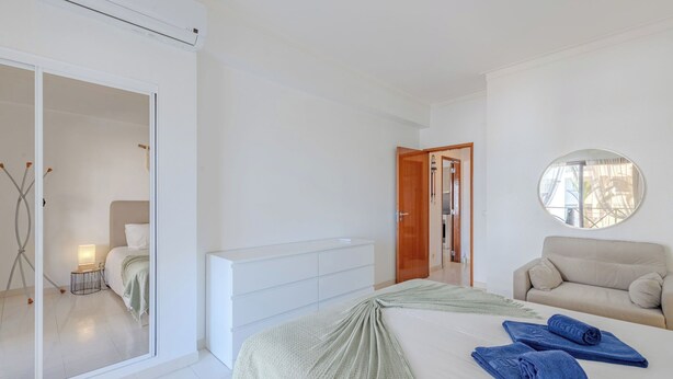Ein modernes Schlafzimmer mit Bett, Schlafsofa, Spiegel und Kleiderschrank.