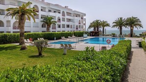Ein Hotel mit Pool, Palmen und Meerblick.