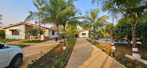 A residential area with houses, a paved pathway, and palm trees. - Shambhala Lake View Villa Resort (Avate)