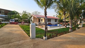 Ein kleines Haus mit Pool, umgeben von Palmen und einem gepflasterten Weg.