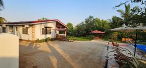 A building with a red roof, a patio area with outdoor furniture, and a pool. - Shambhala Lake View Villa Resort (Avate)