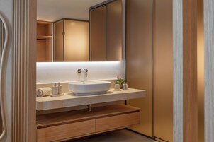 A modern bathroom with a large mirror, a vessel sink, and wooden cabinetry.