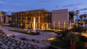 Un bâtiment moderne doté de grandes fenêtres en verre, d’un jardin bien entretenu et d’un chemin aménagé menant à l’entrée.