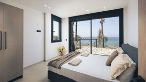 Ett sovrum med en stor säng, en garderob, utsikt över havet och en balkong med en pergola.