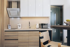 Una cocina moderna con microondas, cafetera y una silla de madera.