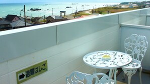 A balcony with a view of the sea, a small table, and a chair. - Pension Villa Commons (Choshi)