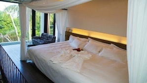A large bed with white linens, a wooden headboard, and a view of greenery outside. - The Seven Stars Resort (Ishigaki)