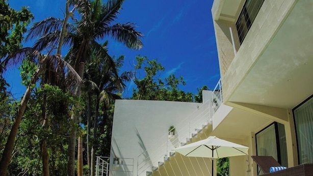 A modern pool area with clear water, a white building, and palm trees. - The Seven Stars Resort (Ishigaki)