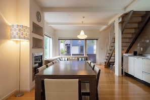 A modern kitchen with a dining area, wooden flooring, and a staircase. - Fo Sho Sanso (Kutchan)