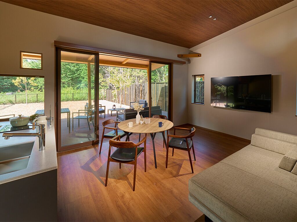 A modern living room with a wooden floor, a round dining table, and a sofa.