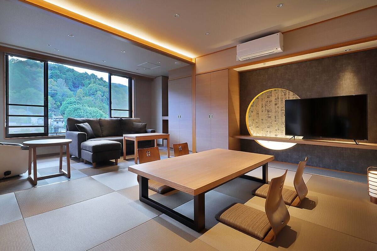 Una sala de estar moderna con un sofá, una mesa de comedor y un televisor montado en la pared.