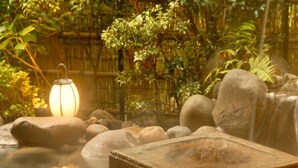 A tranquil indoor garden with a hot tub, rocks, and a lantern.