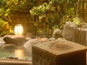 Un jardin intérieur paisible, agrémenté d’un jacuzzi, de rochers et d’une lanterne.