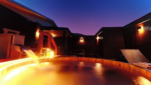 A heated outdoor pool area with wooden structures and seating.