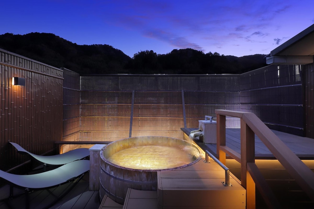 Un bain à remous installé dans un cadre extérieur en bois, avec vue sur les collines.