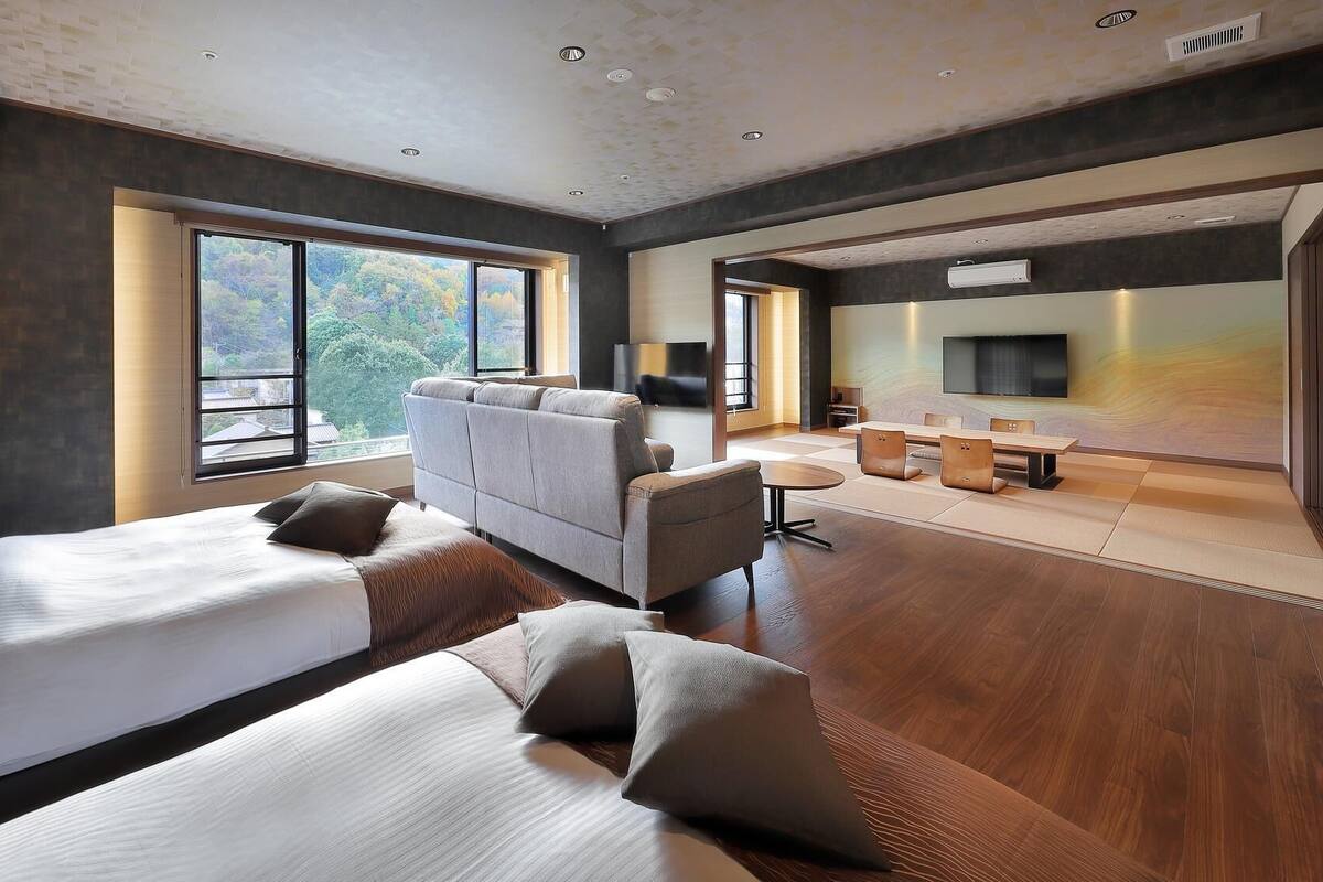 Una habitación de hotel moderna con dos camas, un sofá, un televisor y un comedor.