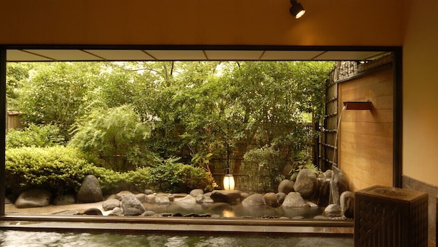 A traditional Japanese interior with a view of a lush garden through a large window.