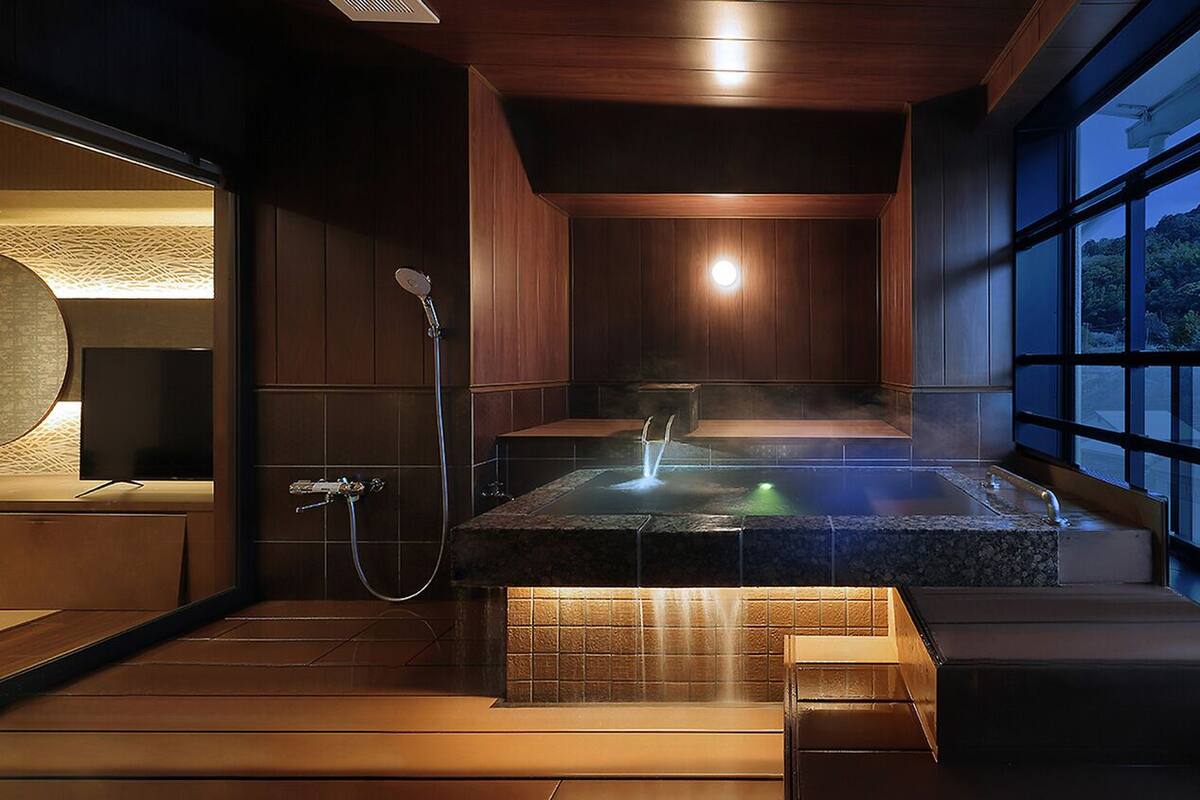 Un moderno cuarto de spa con hidromasaje, ducha y vistas a un paisaje montañoso.