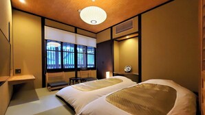 Una habitación con cama, una mesita, una silla, una ventana y una lámpara en el techo.