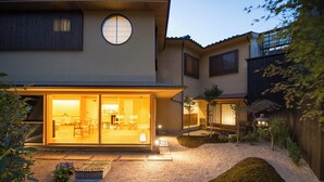 Una casa moderna con un amplio acceso de vidrio, un pequeño jardín y un farol japonés tradicional.