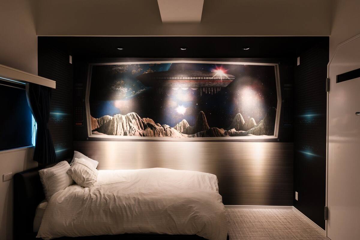 Ein Schlafzimmer mit einem großen Bett, einem an der Wand befestigten Fernseher und einem Wandbild einer Berglandschaft.