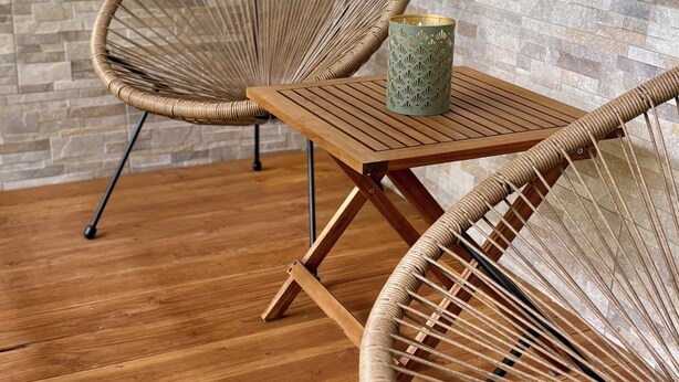 Two wicker chairs with a woven pattern, a small table, and a decorative vase.