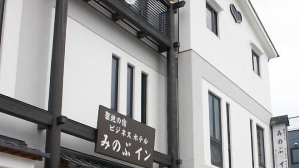 Un bâtiment avec une enseigne en japonais, un balcon et une fenêtre ornée d’un motif en treillis.