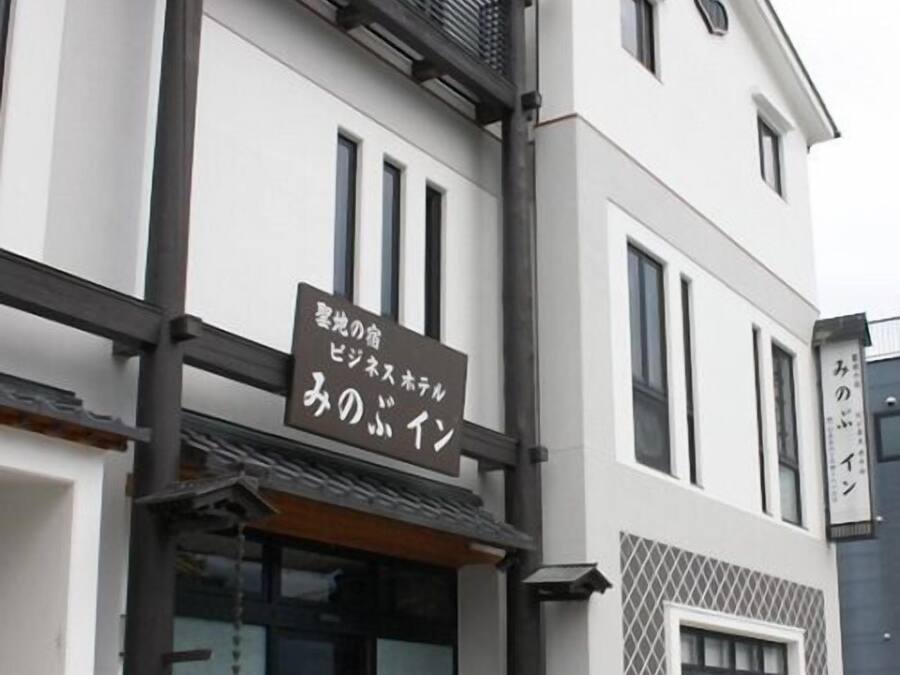 A building with a sign in Japanese, a balcony, and a window with a lattice design.