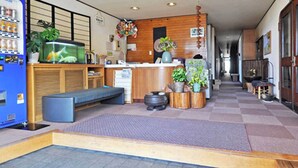 A reception area with a counter, seating, a fish tank, and potted plants.