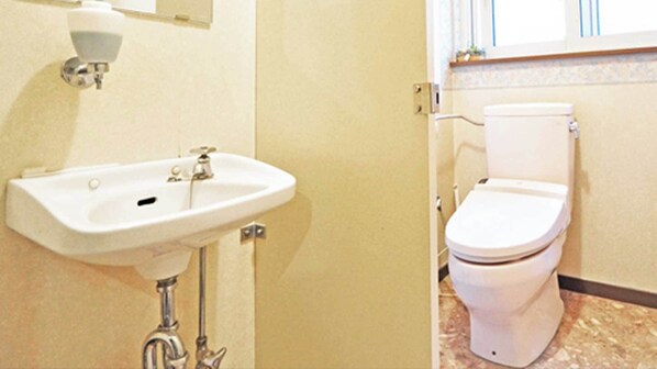 A bathroom with a white sink, a toilet, and a window.