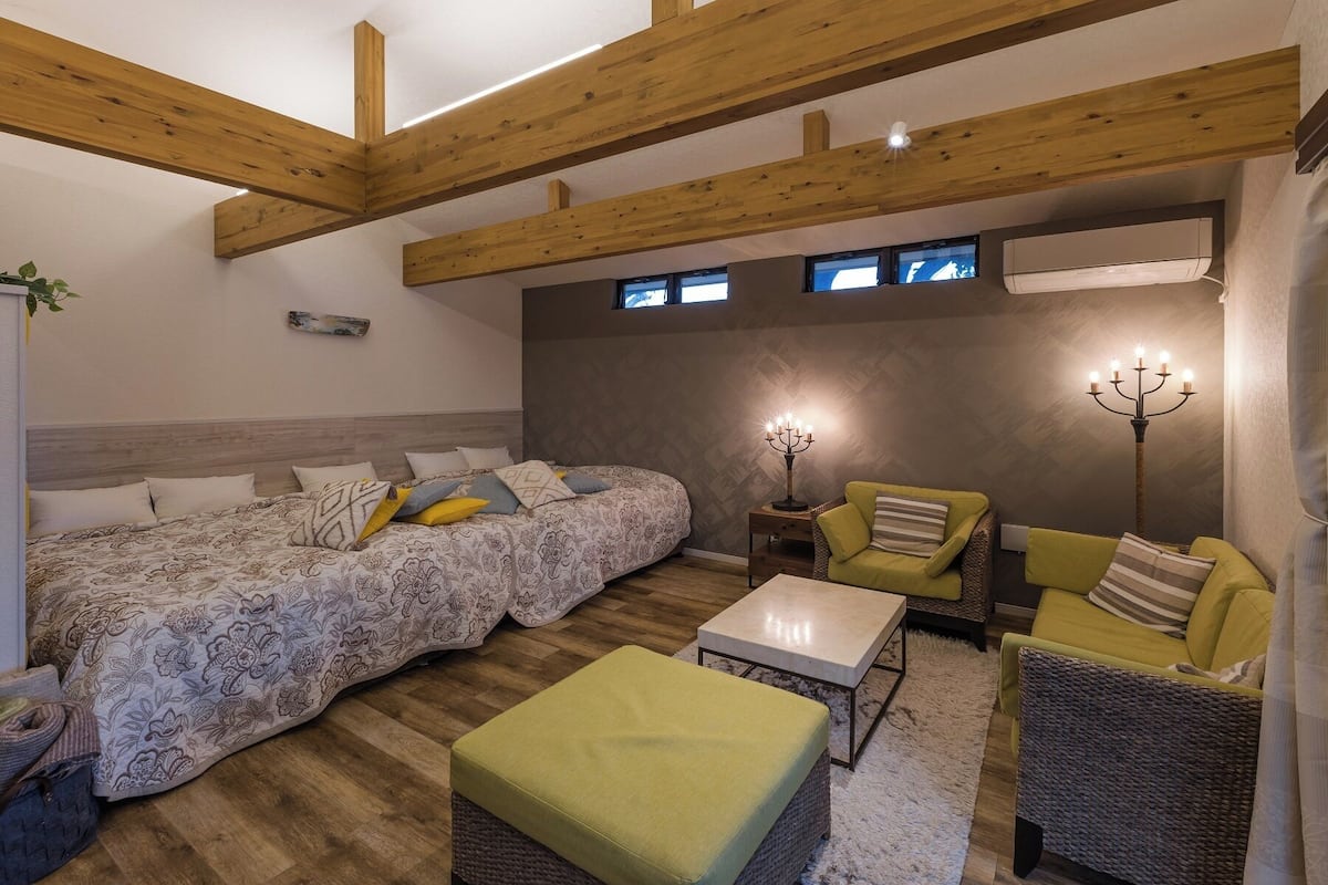 Ein Zimmer mit einem Bett, zwei Sessel, einem kleinen Tisch und einem Kandelaber.