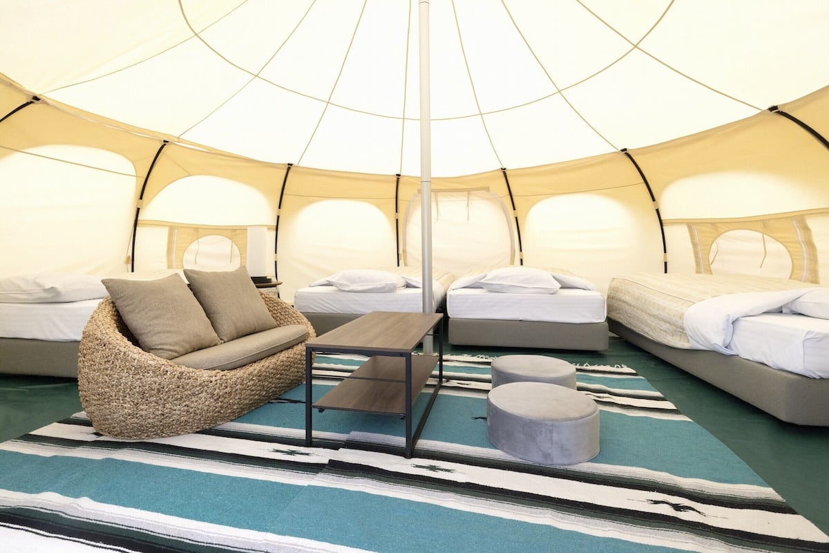 Eine Zelthütte mit mehreren Betten, einer Couch und einem Tisch.