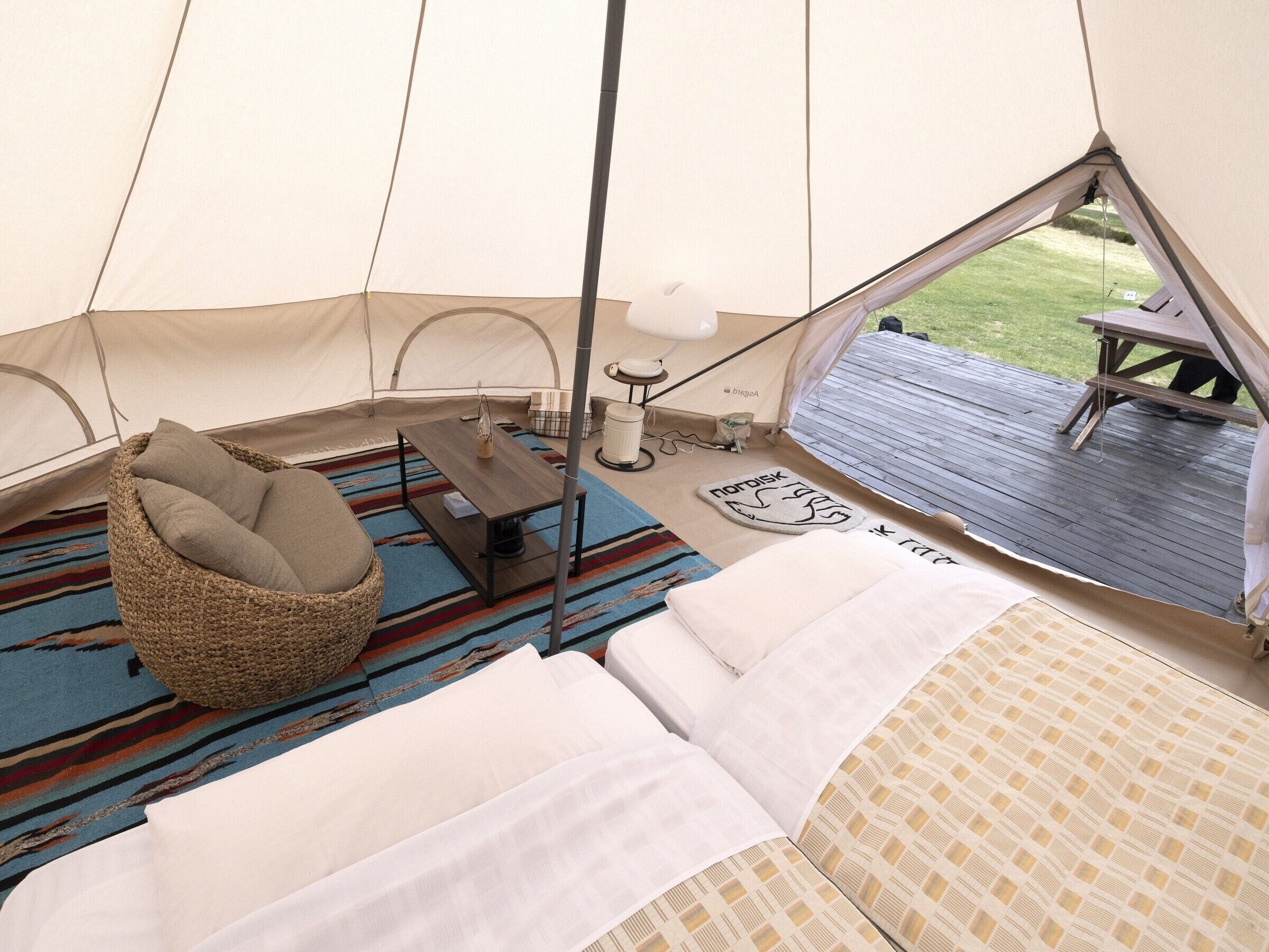 Una carpa con cama, una silla, una mesa y vistas al exterior.