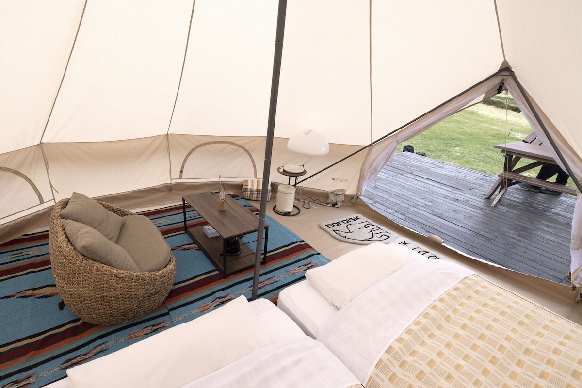 Ein Zelt mit Bett, Stuhl, Tisch und Blick ins Freie.