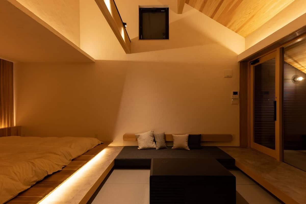 Ein modernes Zimmer mit einem Bett, einer kleinen Couch und einer Schiebetür.