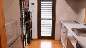 Una cocina estrecha con suelo de madera, un refrigerador, un lavavajillas y armarios.