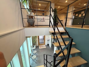 Interior de hotel com vários níveis, escadaria, área de estar e balcão de recepção.