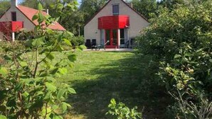 Una casa con tetto rosso, un portico e un prato.