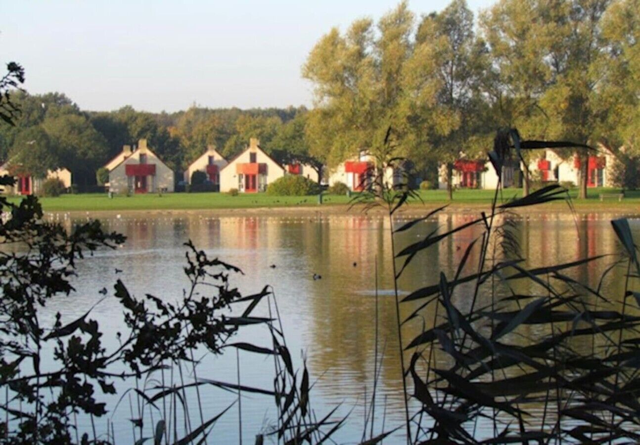 Une rangée de maisons au bord d’un lac paisible, sous un ciel dégagé.