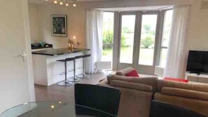 Un soggiorno moderno con un tavolo da pranzo in vetro, un divano e una televisione.