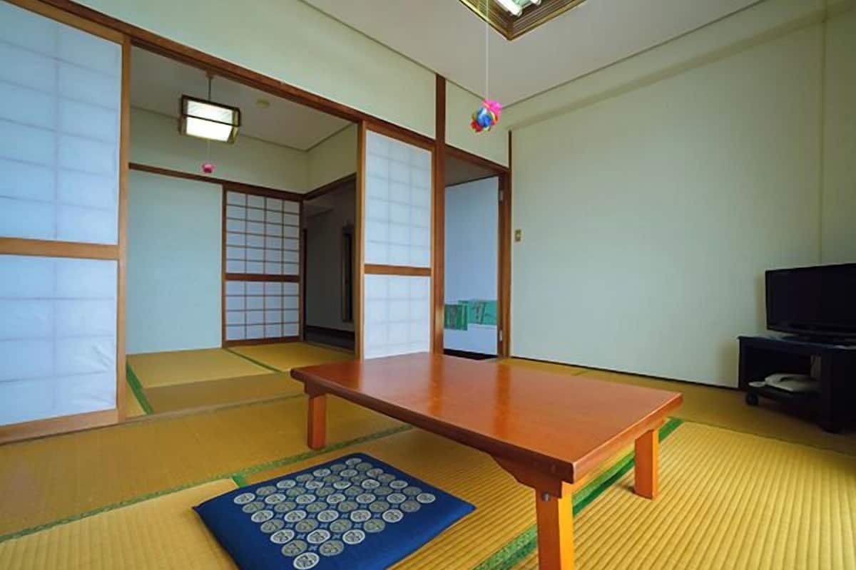 A traditional Japanese room with tatami flooring, a low wooden table, and sliding doors.