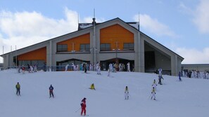 Et skiområde med en stor bygning, skipister og skiløbere.