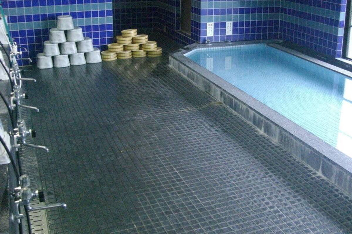 A swimming pool with tiled walls and a tiled floor, surrounded by stacks of white and gold cylindrical objects.