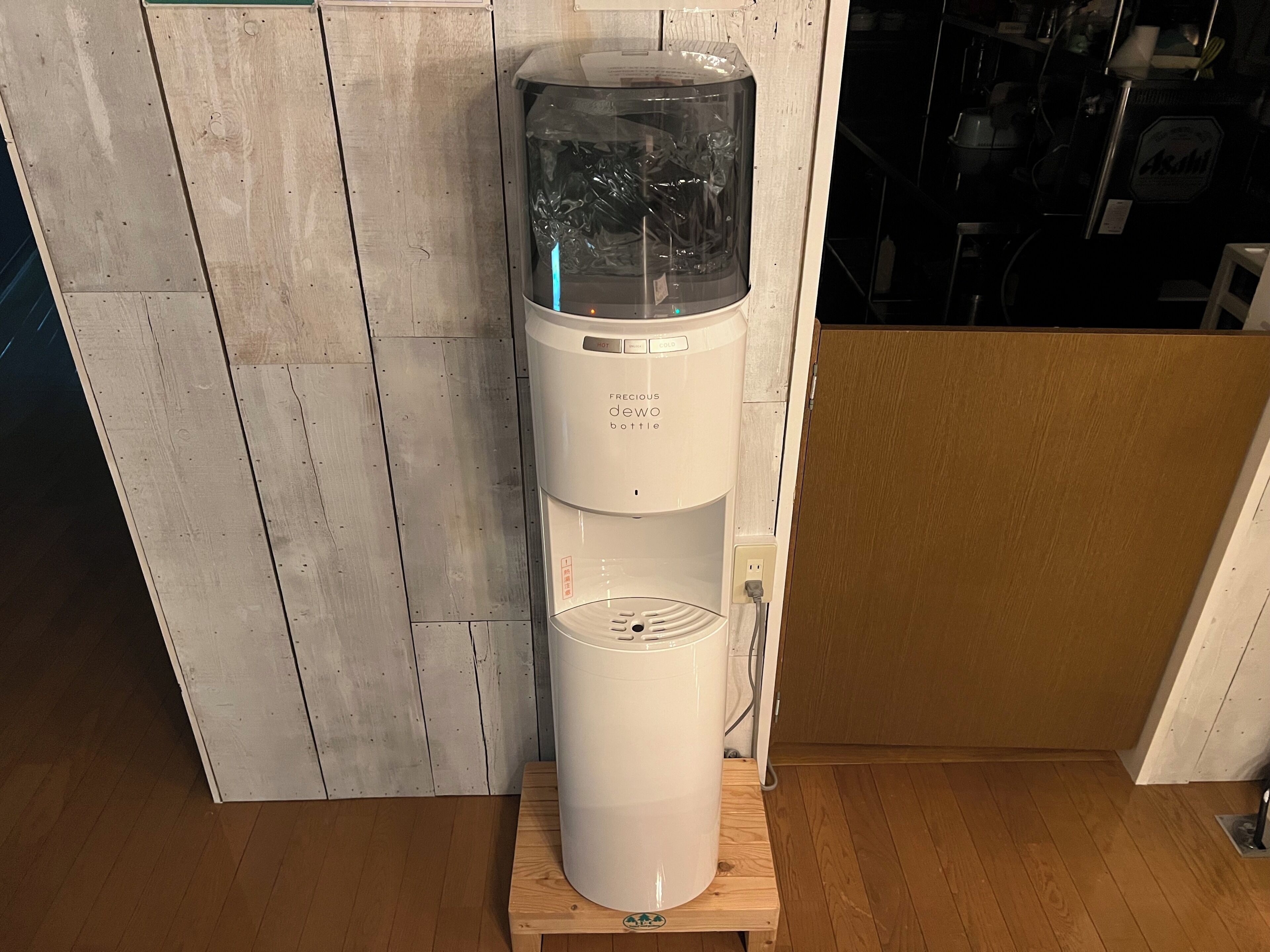 A freestanding coffee maker with a transparent water reservoir, a control panel with temperature settings, and a power outlet.